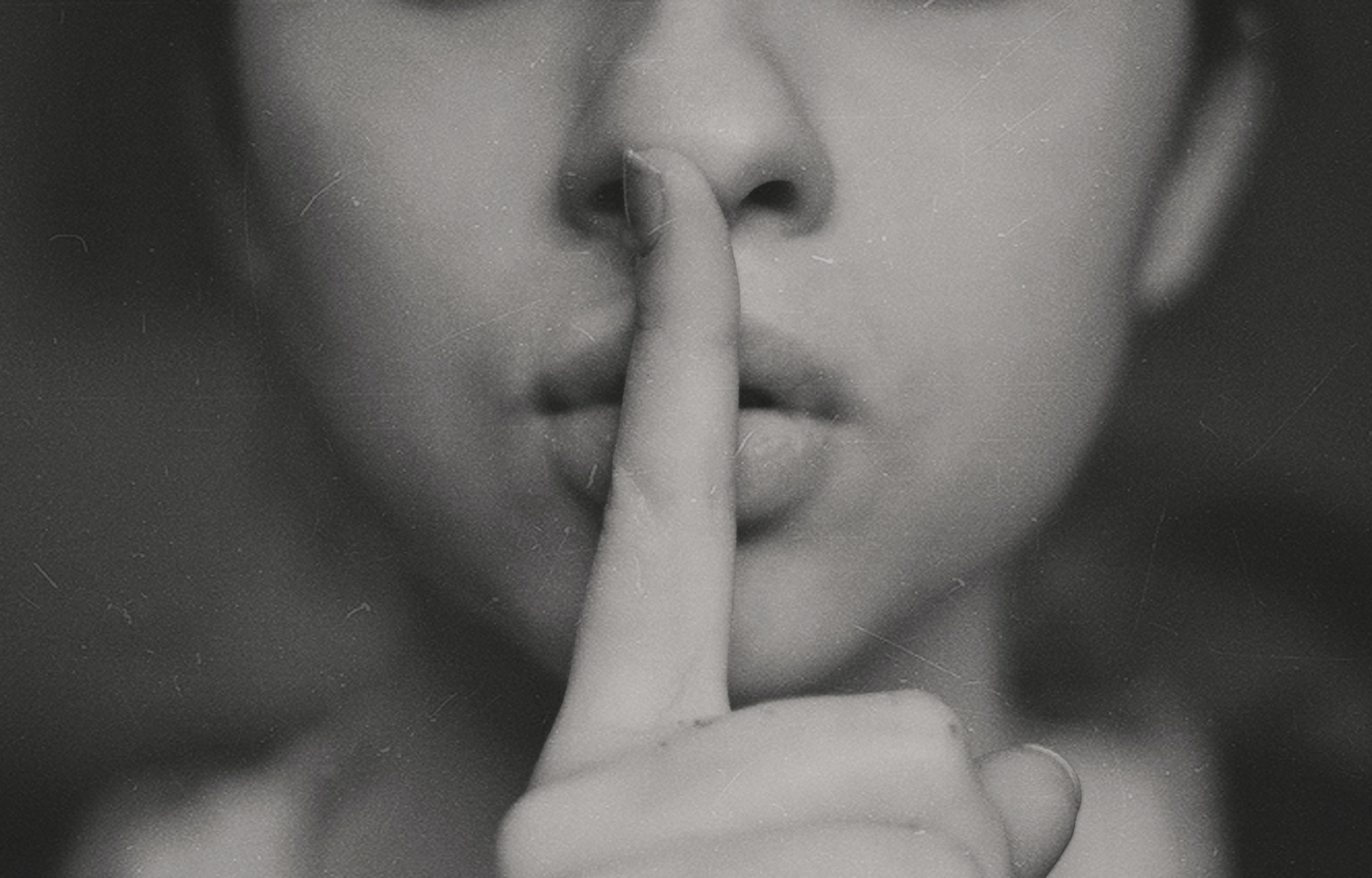 Csendre intő, titkolózó nő puszilgatja az ujját