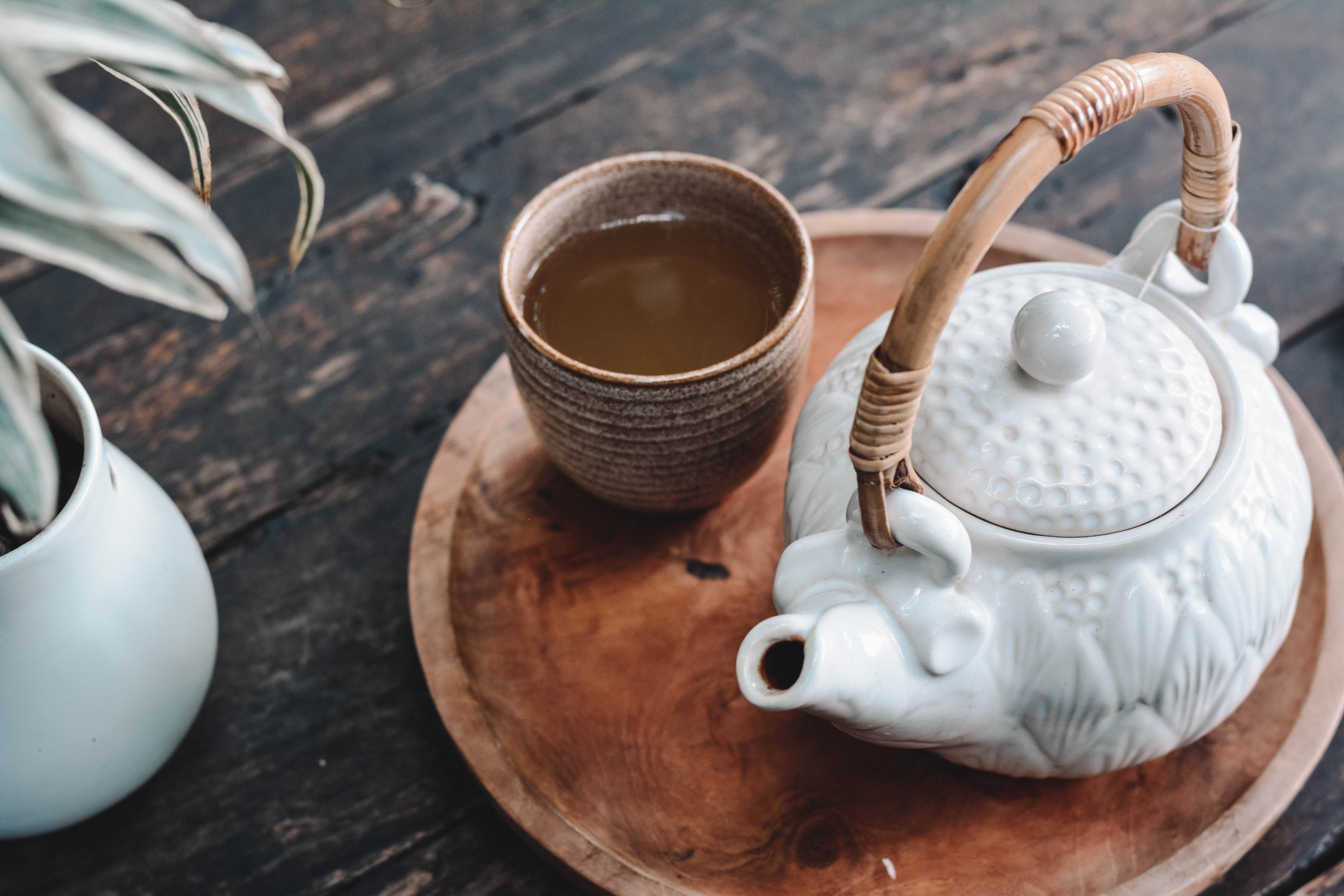 Tea egy csészében, teáskanna mellett, faasztalon