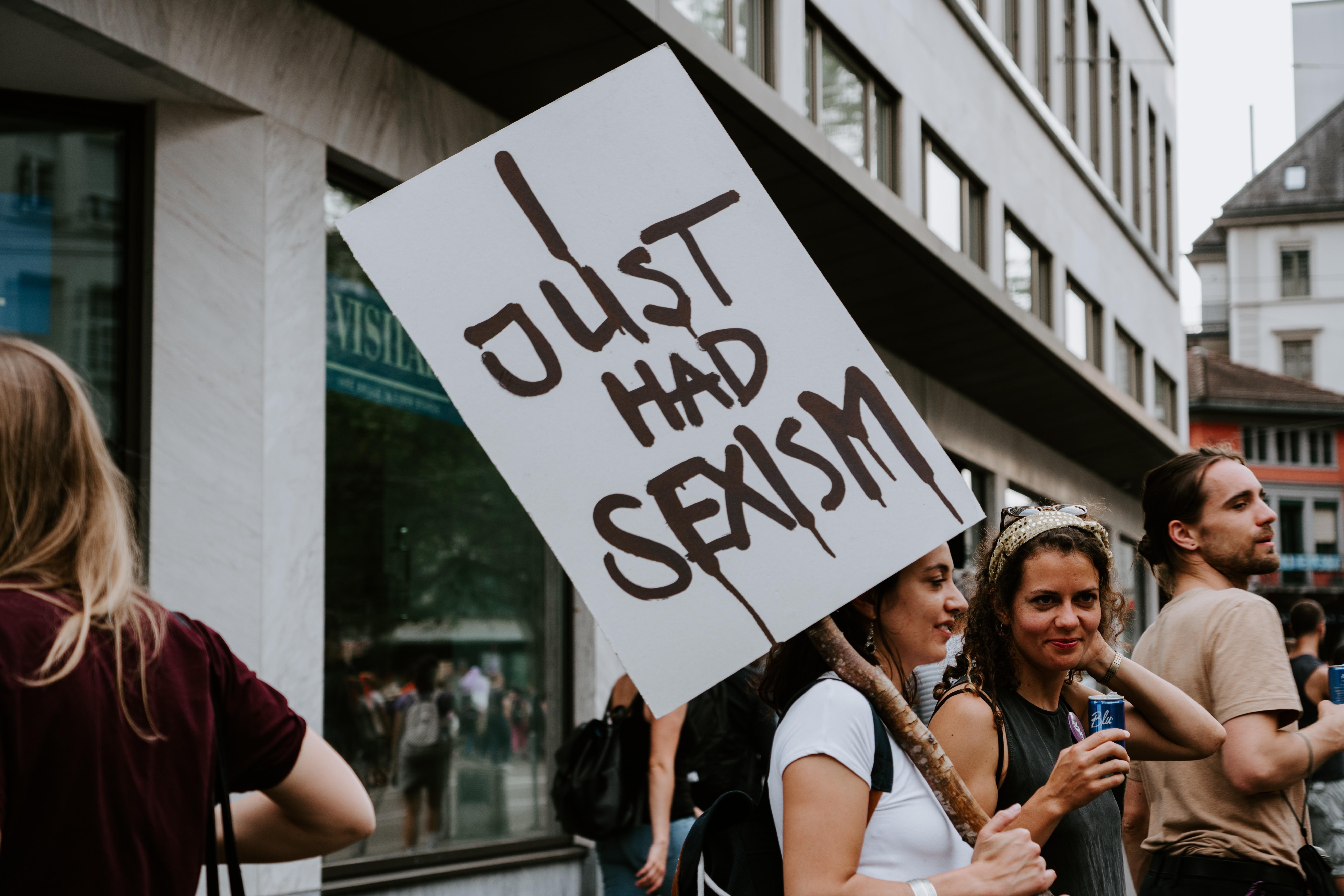 Egy nő szeximussal kapcsolatos táblát tart egy tüntetésen