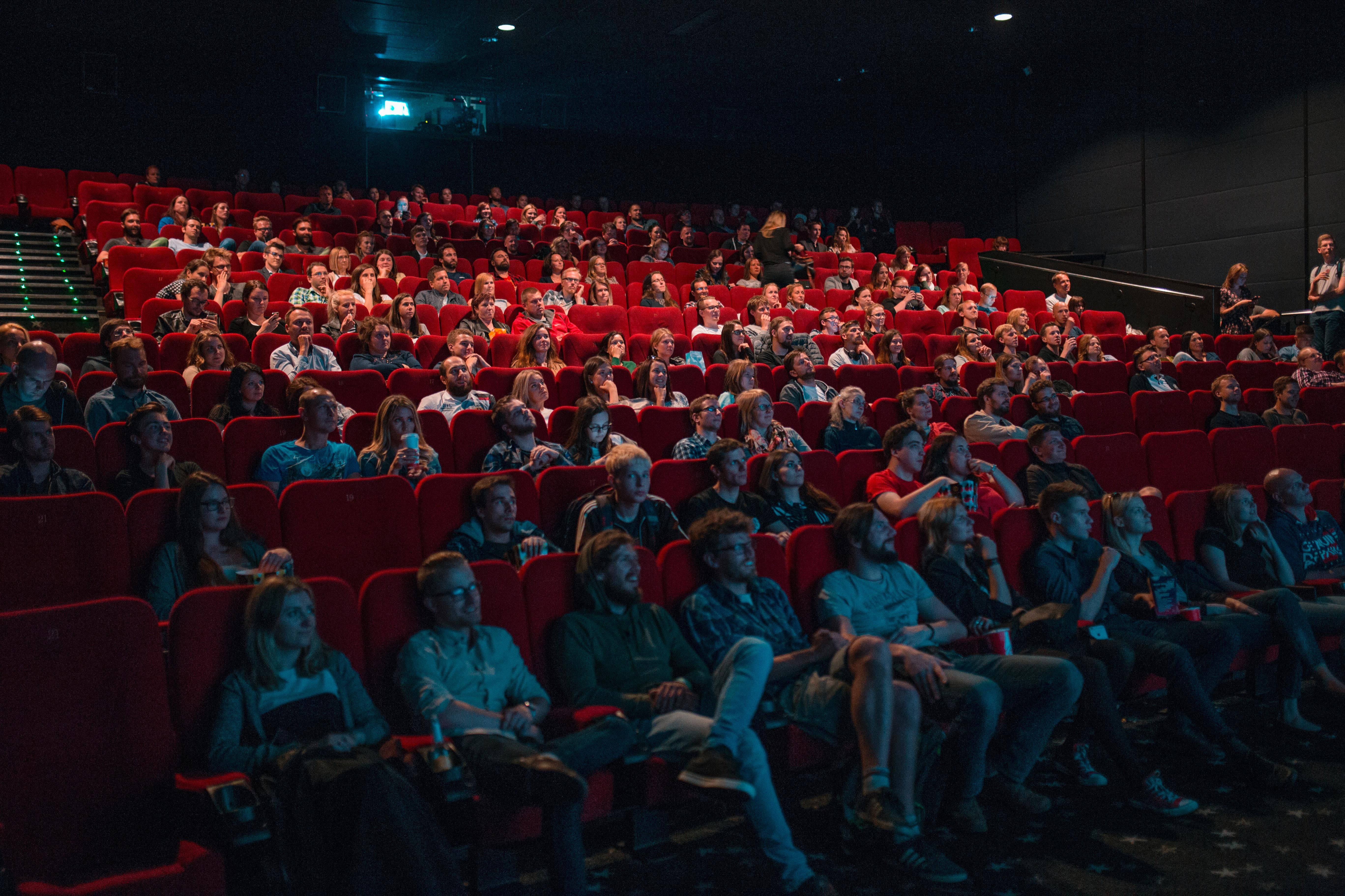 Teltházas moziban nézik az emberek a filmvásznat piros székekről