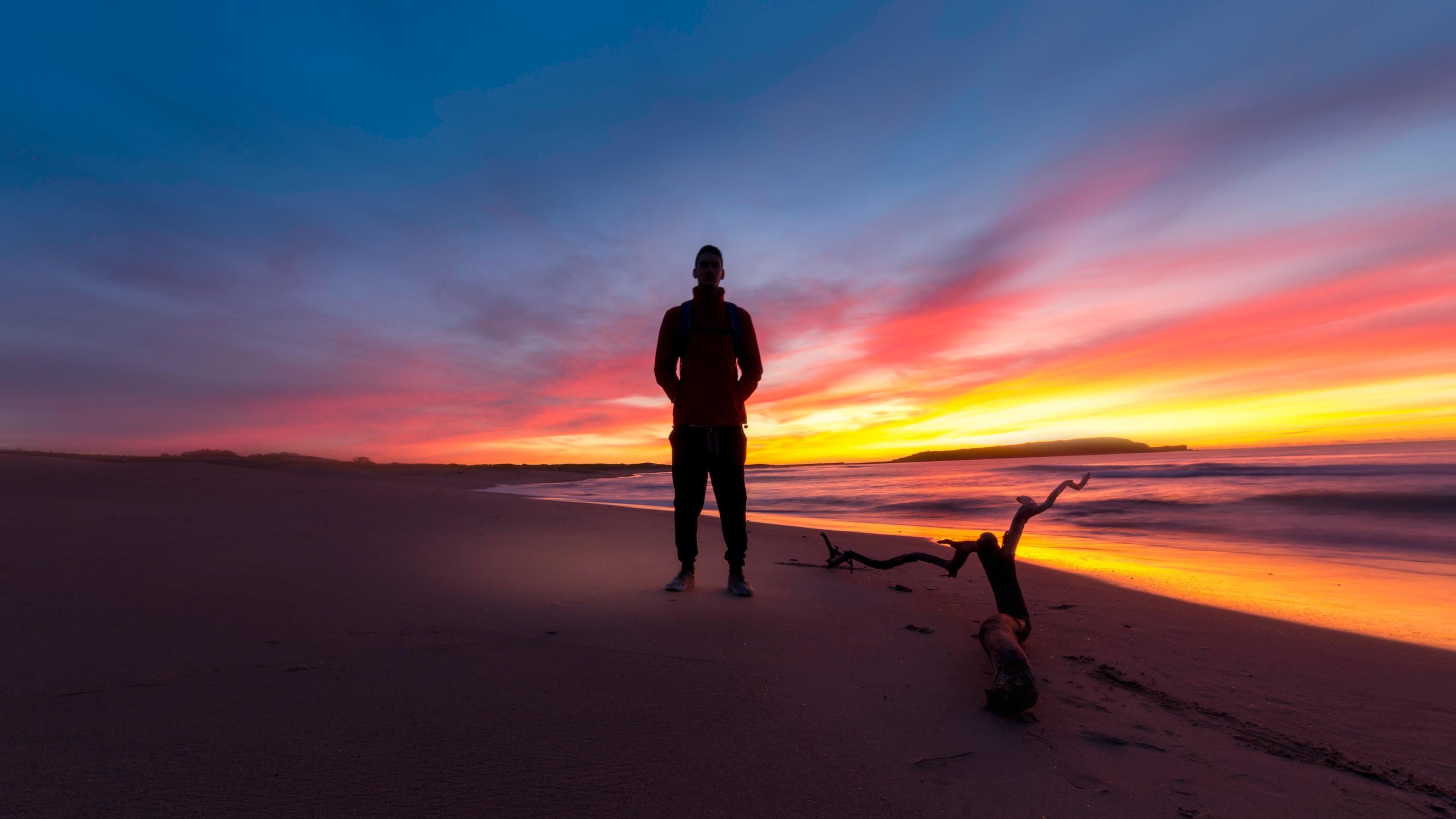 Introvertált ember áll a tengerparton naplementében