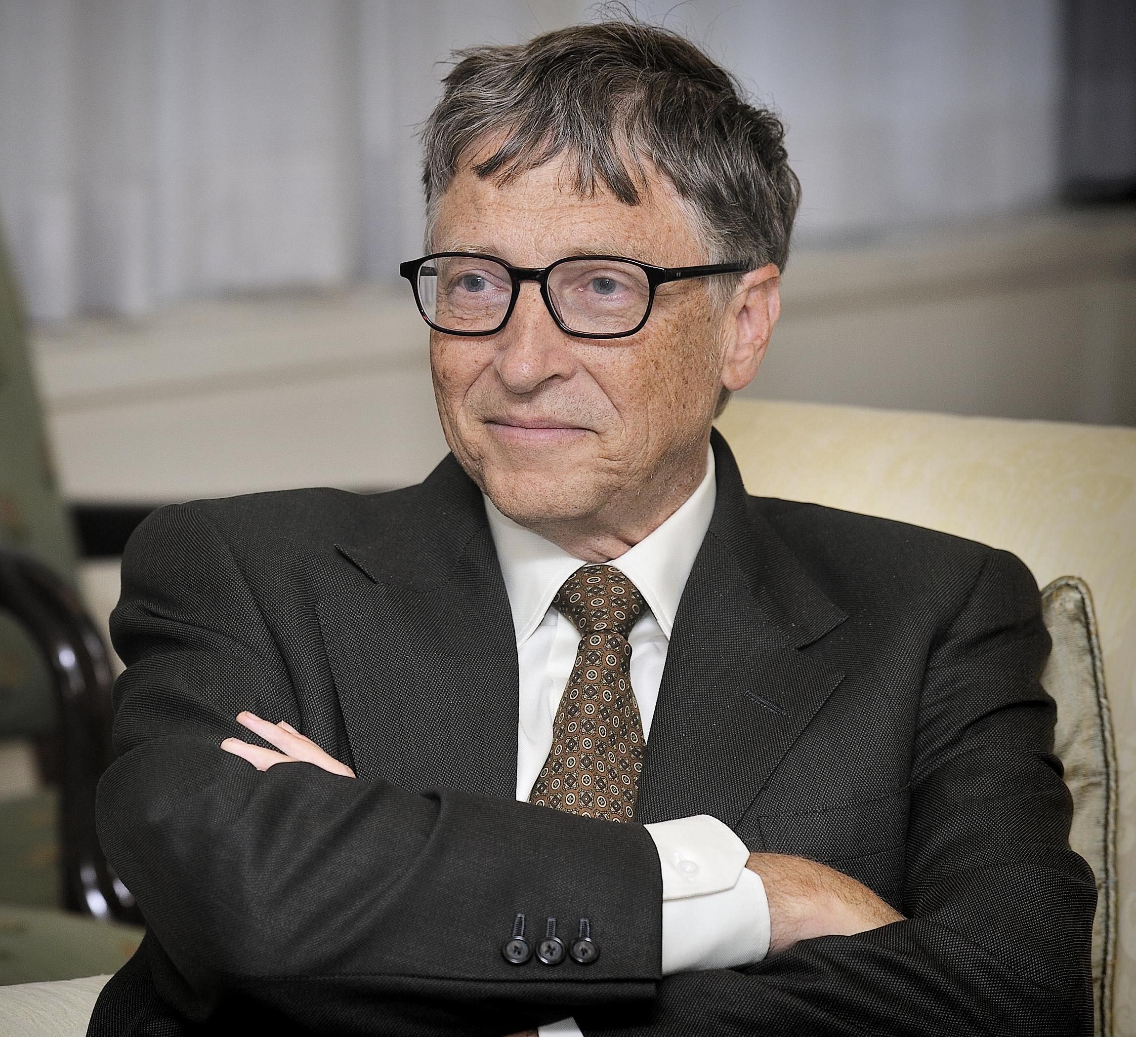 Bill Gates keresztbe tett kézzel kémleli a jövőt öltönyben