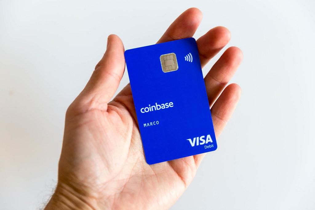 Coinbase Visa kártya egy kézben fehér háttérrel