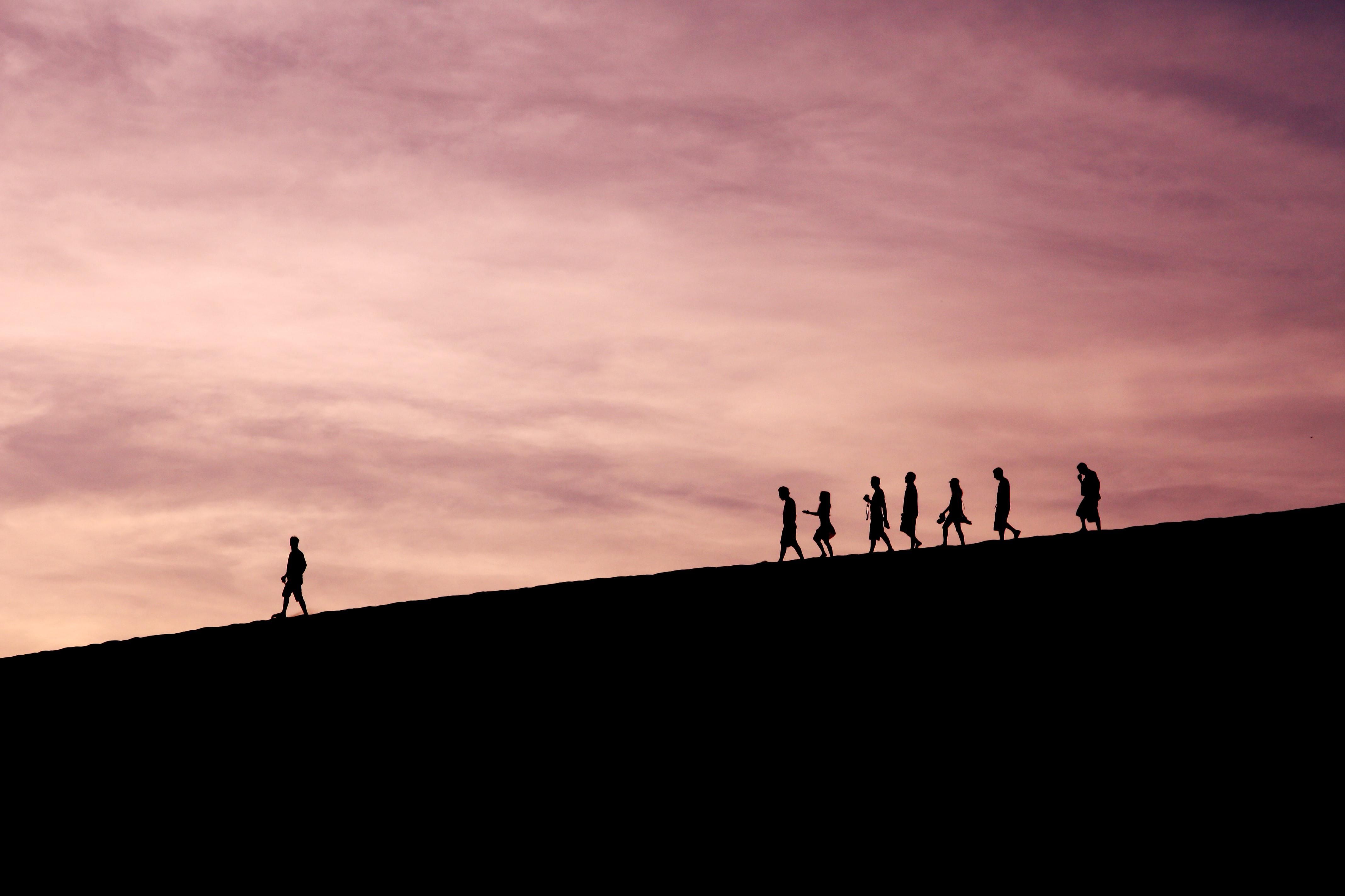 Egy ember vezeti a mögötte lévő hét embert naplementében egy domboldalon