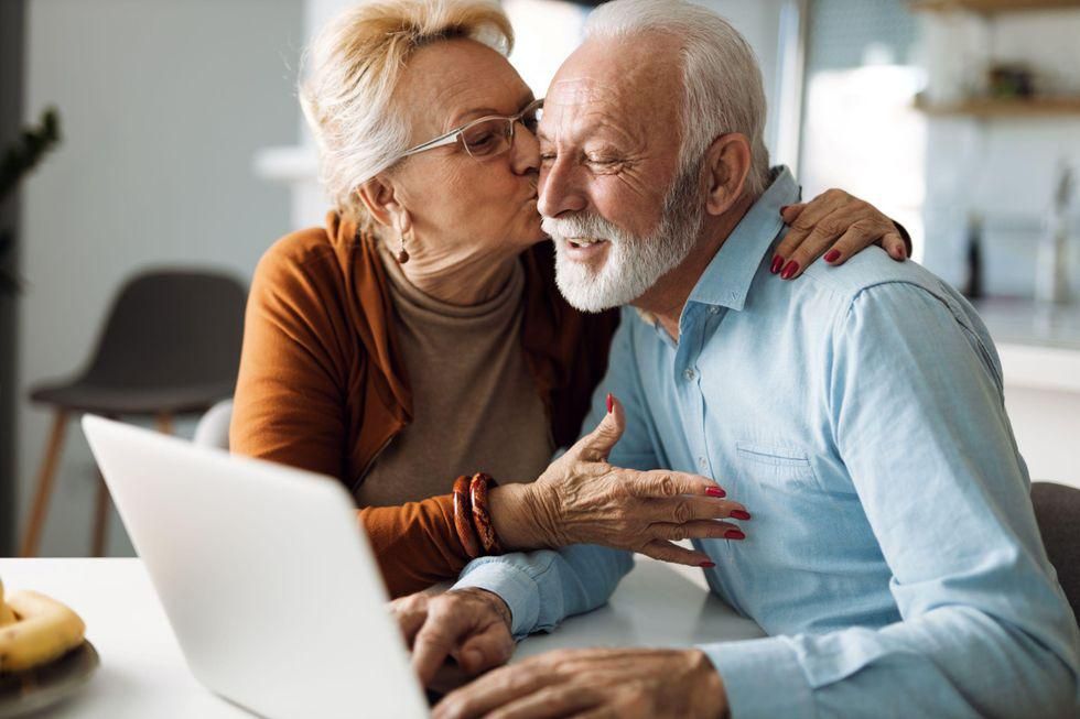 Egy nyugdíjas férfi és nő egy laptop előtt ül. 