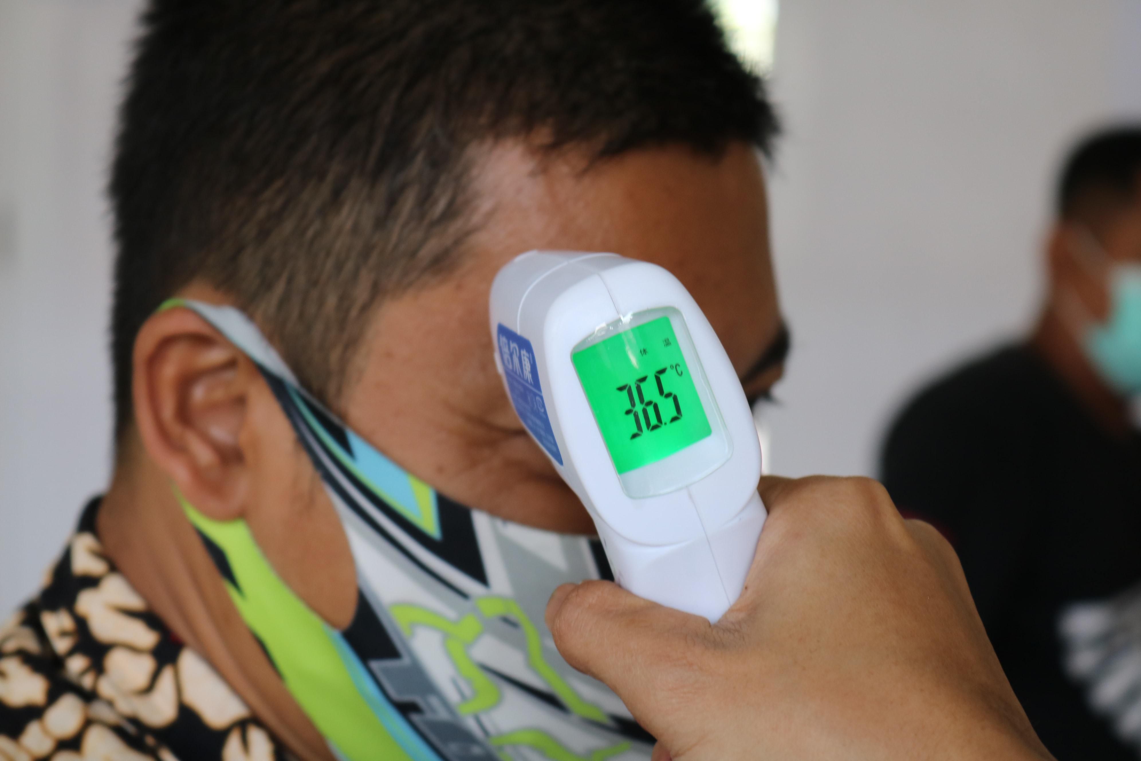 Maszkos Amazon dolgozó testhőmérsékletét ellenőrzik hőmérséklet ellenőrző piztollyal