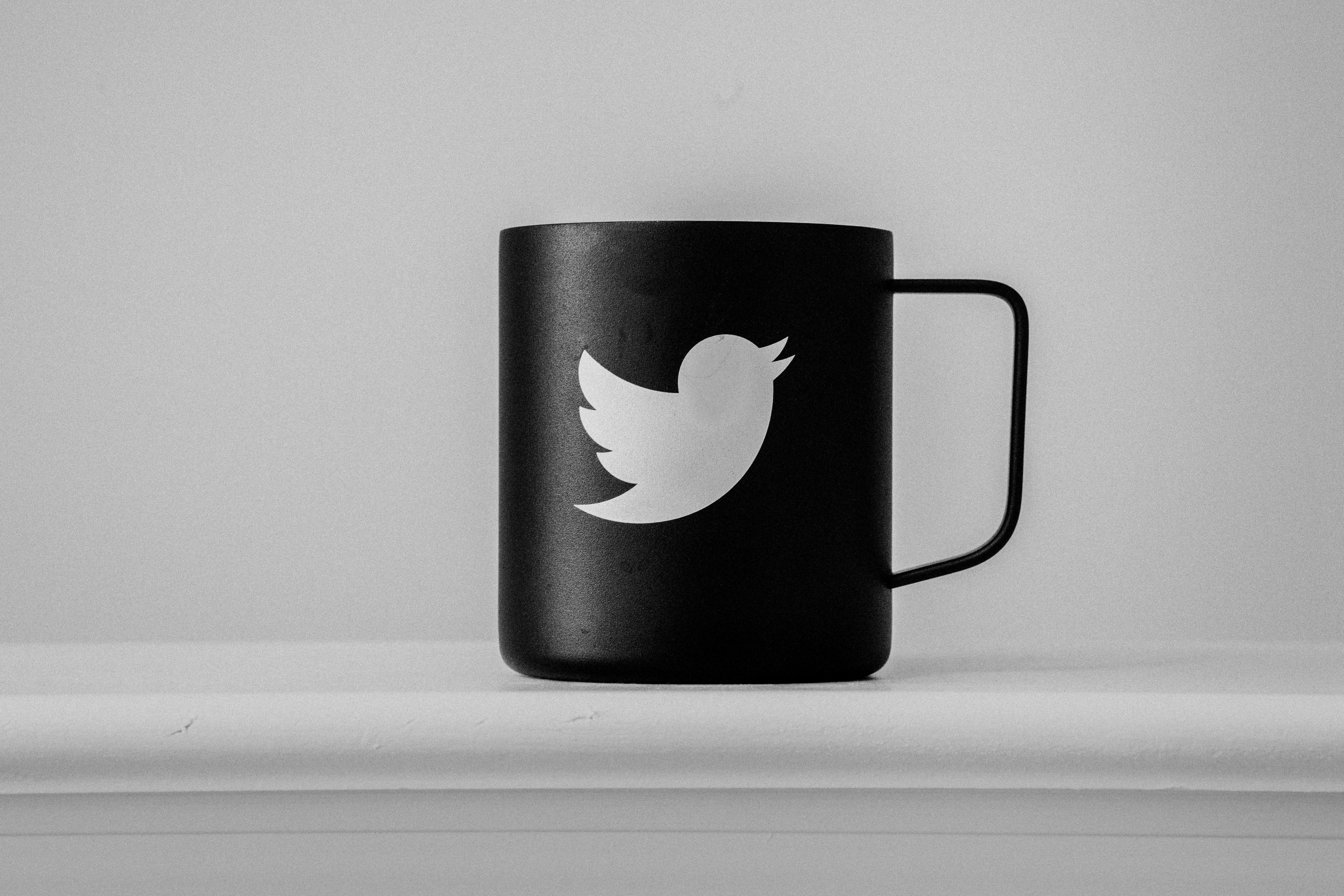 Twitter emblémája egy fekete bögrén fehér környezetben