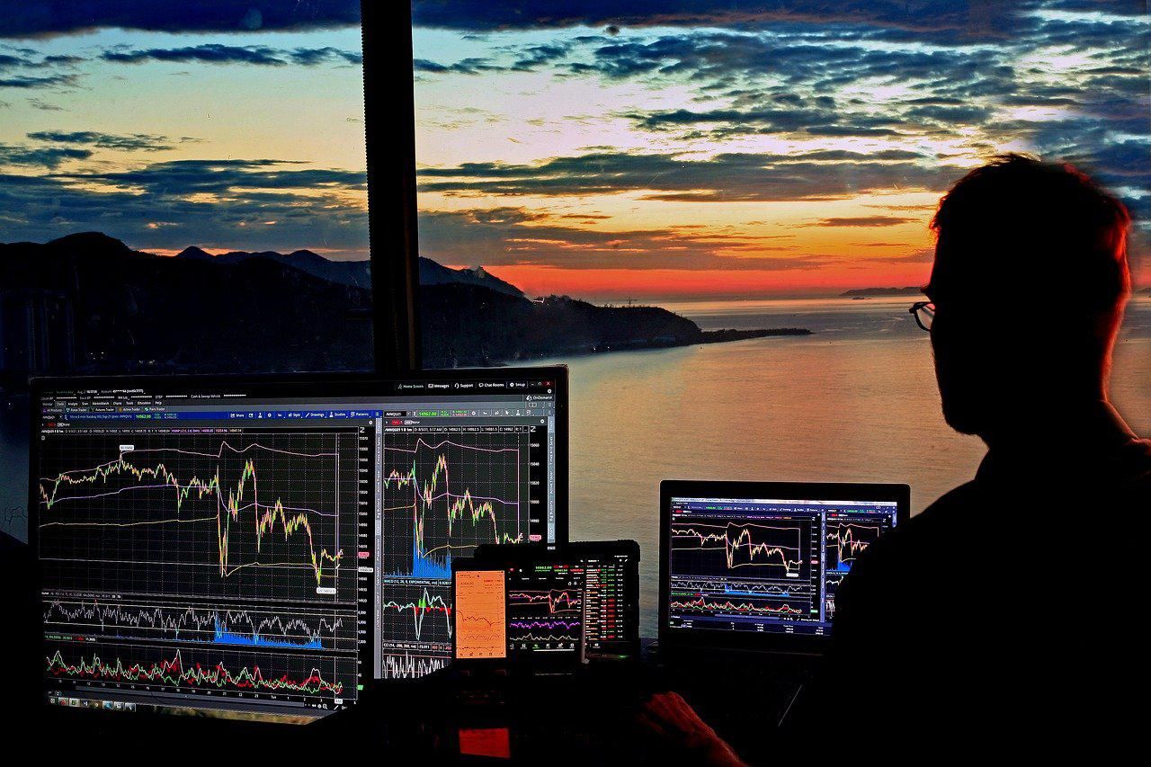 Kockázati tőkés figyeli a részvényárfolyamokat a naplementében a tengerparti háza ablakában
