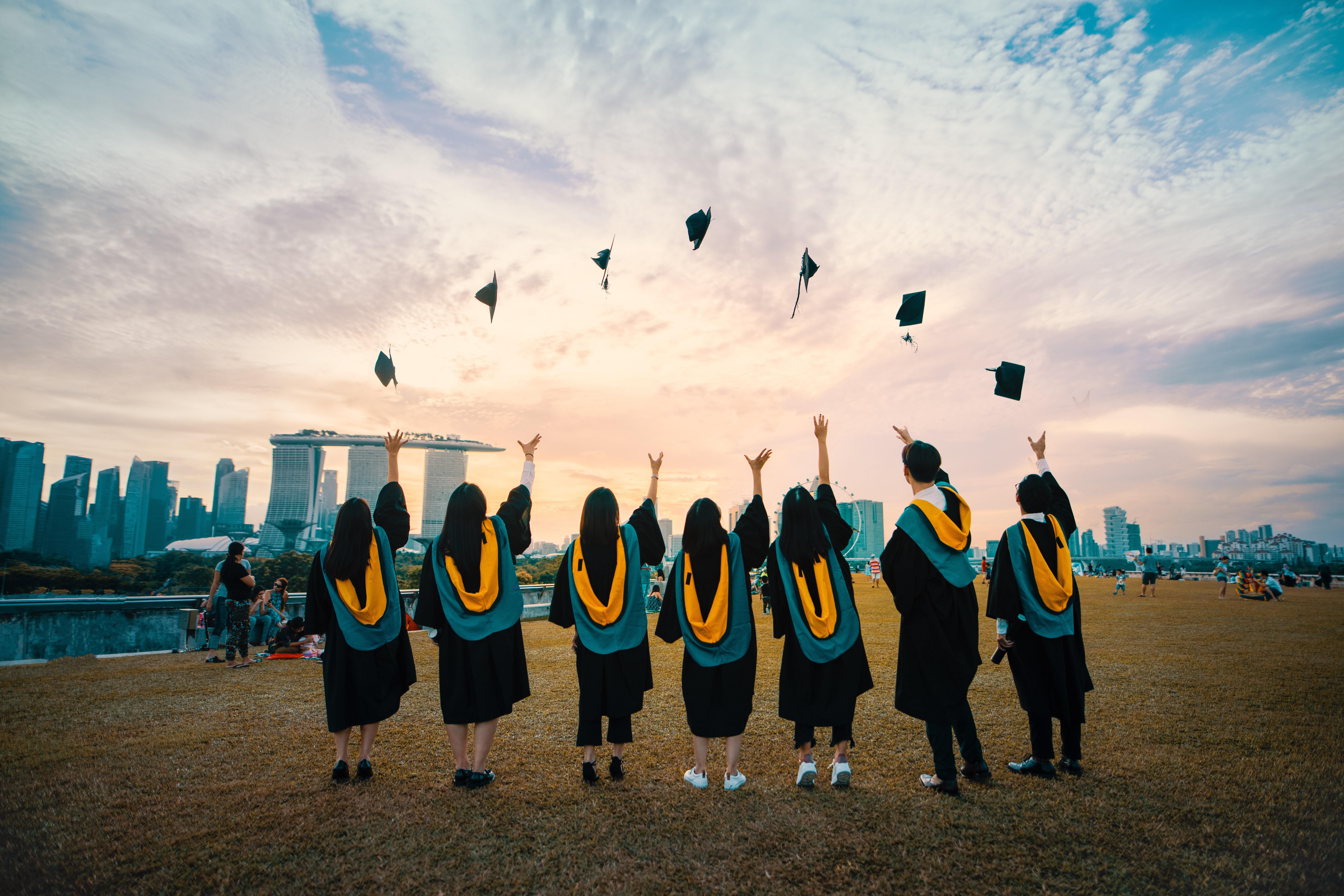 Szingapúri végzős kriptovaluta diákok magasba dobják a kalapjukat sikeres egyetemi  államvizsga után, Szingapúrban