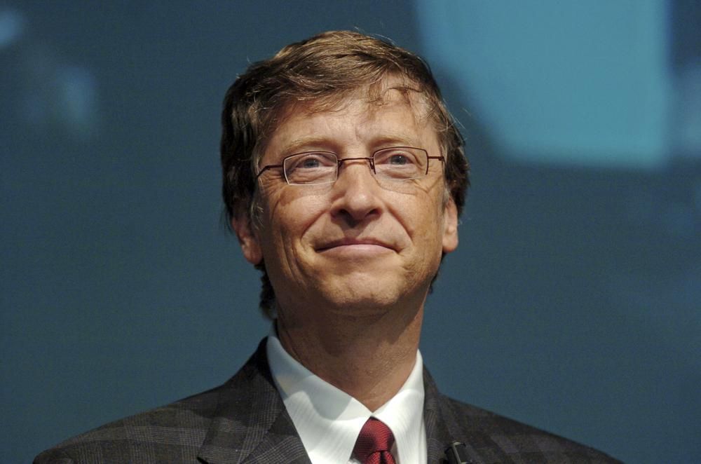 Bill Gates szemüvegben, öltönyben, piros nyakkendőben büszkén nézi a könyve letöltéseinek számát