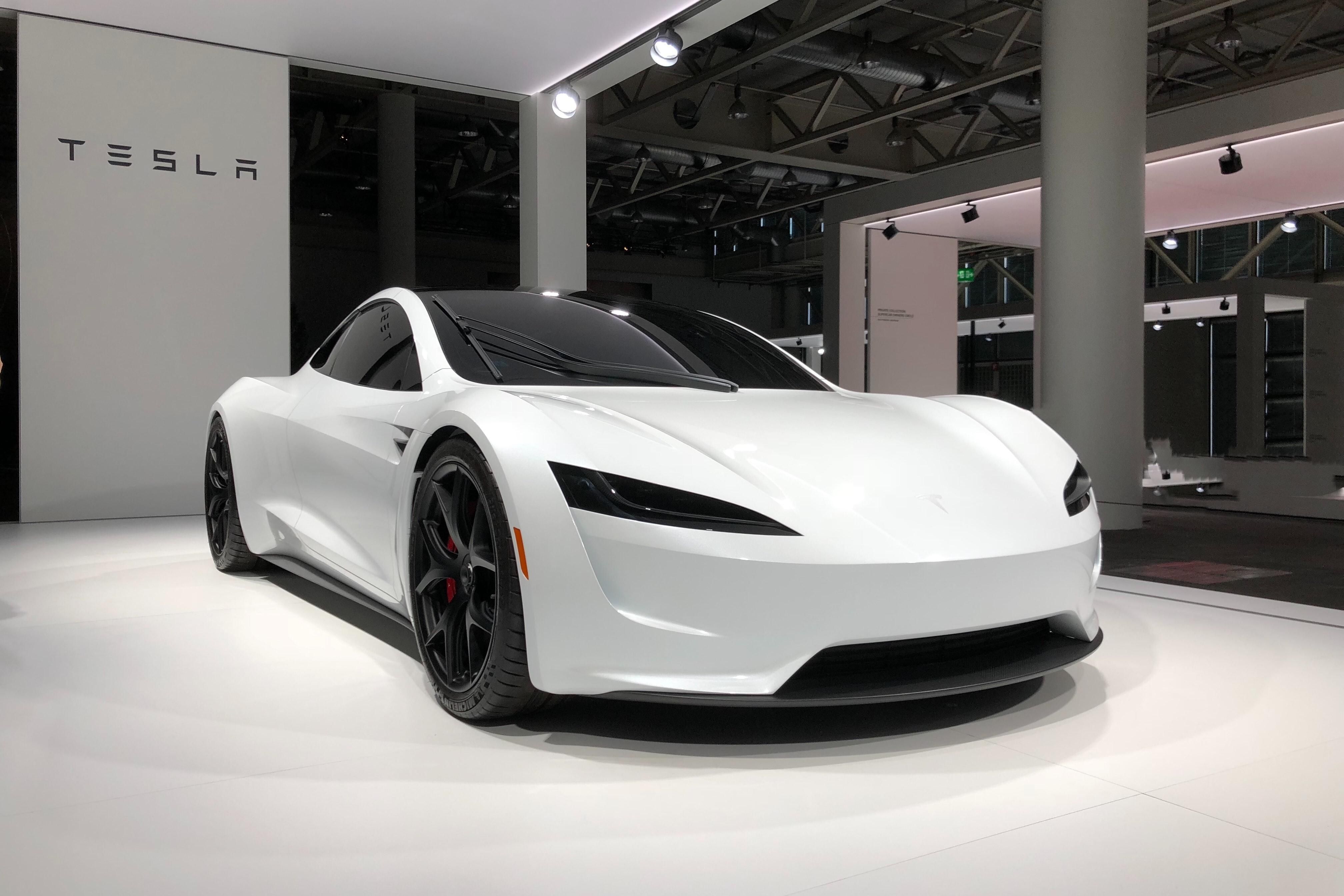 Egy fehér Tesla Roadster áll egy kiállításon a Tesla épületében