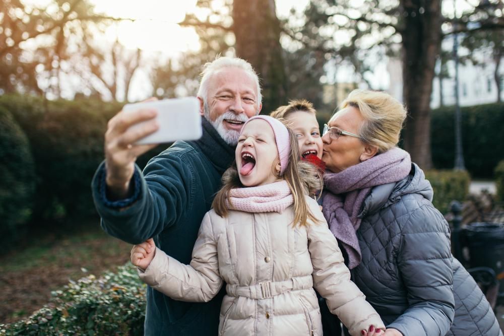 Nagyszülők fényképezkednek az unokáikkal a karácsonyi ajándékozás után