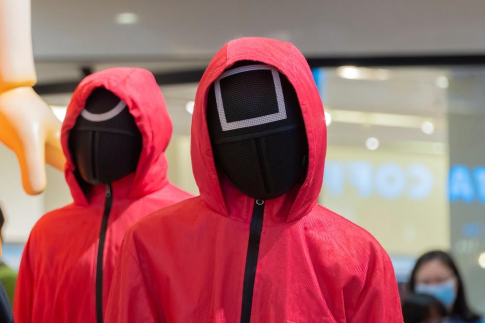 A Netflix Squid Game sorozatából ismert rózsaszín ruhás, fekete maszkos őrök figyelnek valakit