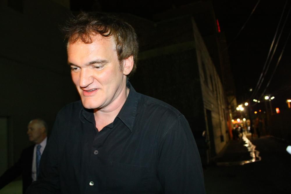Quentin Tarantino fekete ingben mosolyogva sétál a rajongói előtt