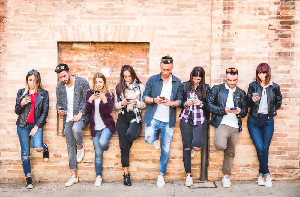 Fiatal felnőttek, az Y generáció tagjai a telefonjukat nyomkodják, és épp arról szavaznak, hogy melyik a kedvenc márkájuk