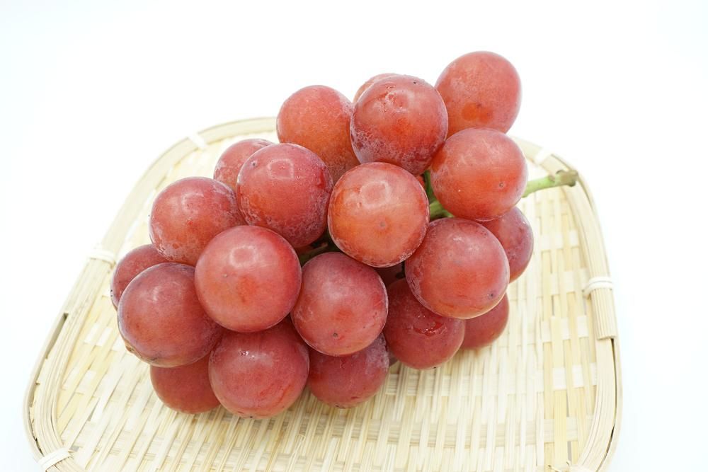 Japán Ruby Roman szőlőfürt vörös, óriási szőlőszemekkel egy bambusztálon, ez a világ legértékesebb szőlője