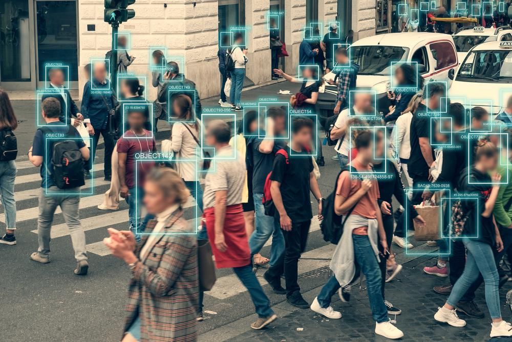 Brit polgárok sétálnak az utcán, ahol egy zebrán épp adatokat gyűjt az arcukról egy arcfelismerő szoftver