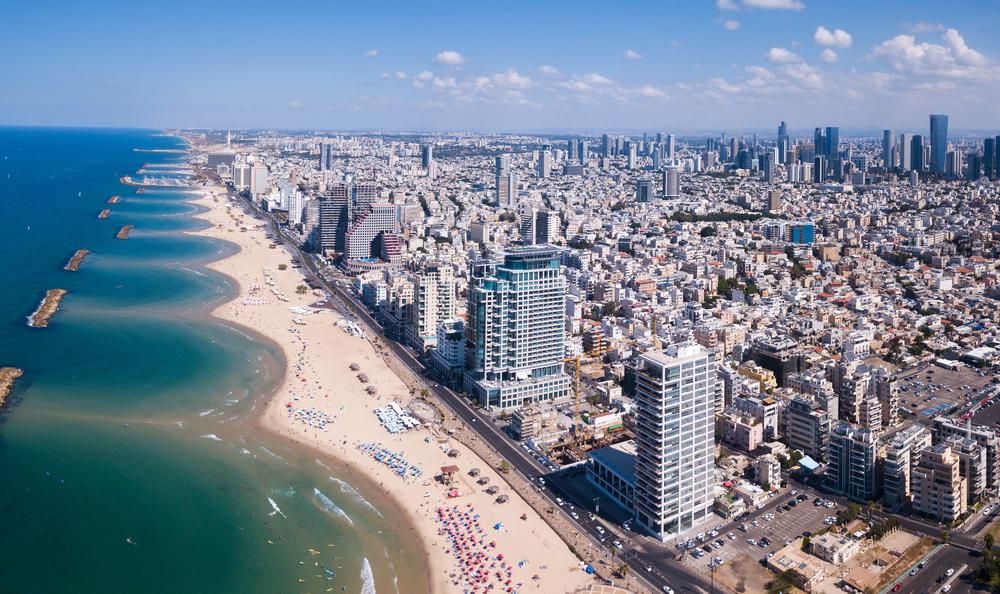 Tel Aviv szállodákkal és házakkal zsúfolt tengerpartja napsütéses időben, Tel Avivban a legdrágább az élet 