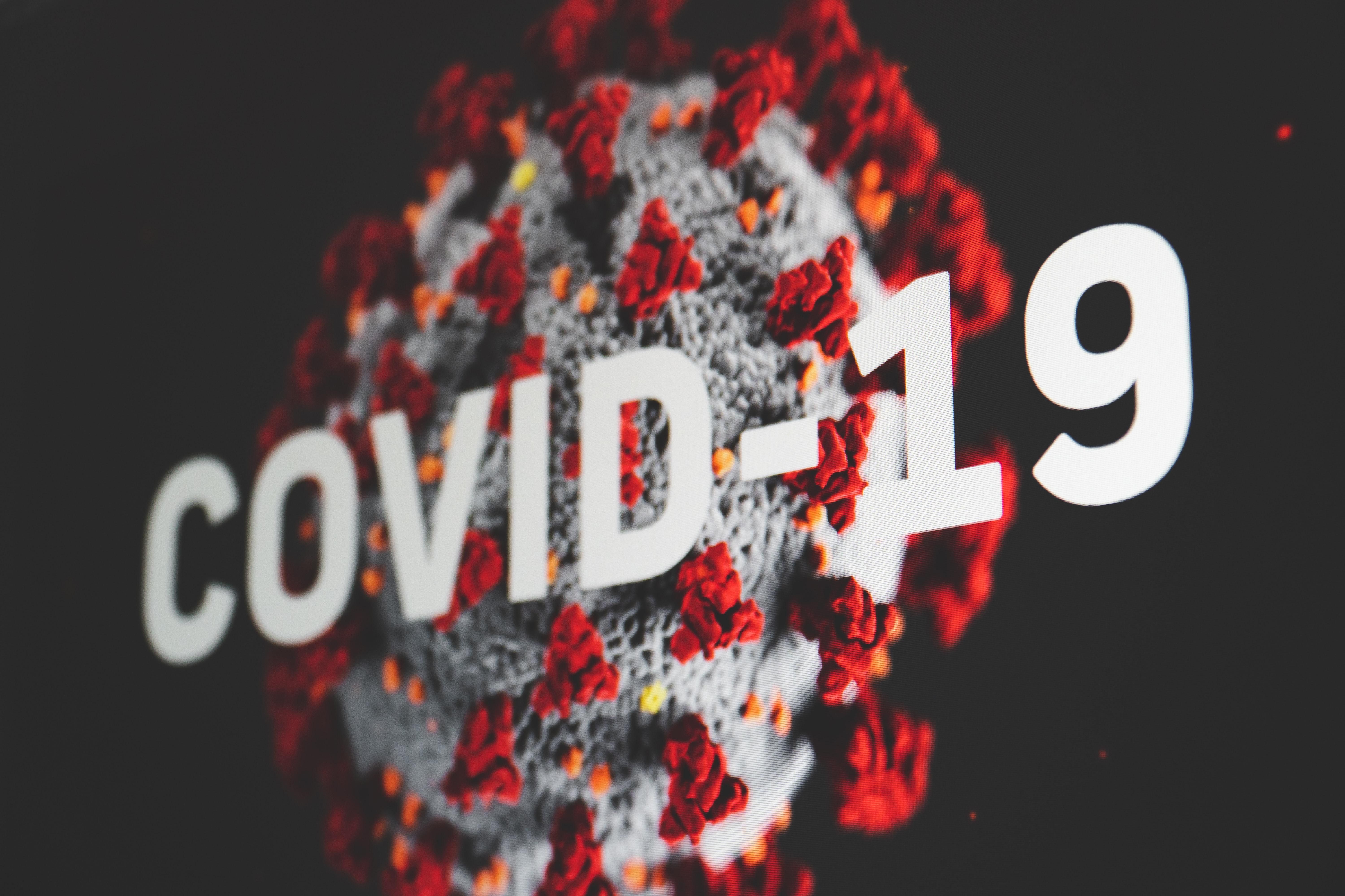 COVID-19 felirat egy piros tüskefehérjés vírus előtt