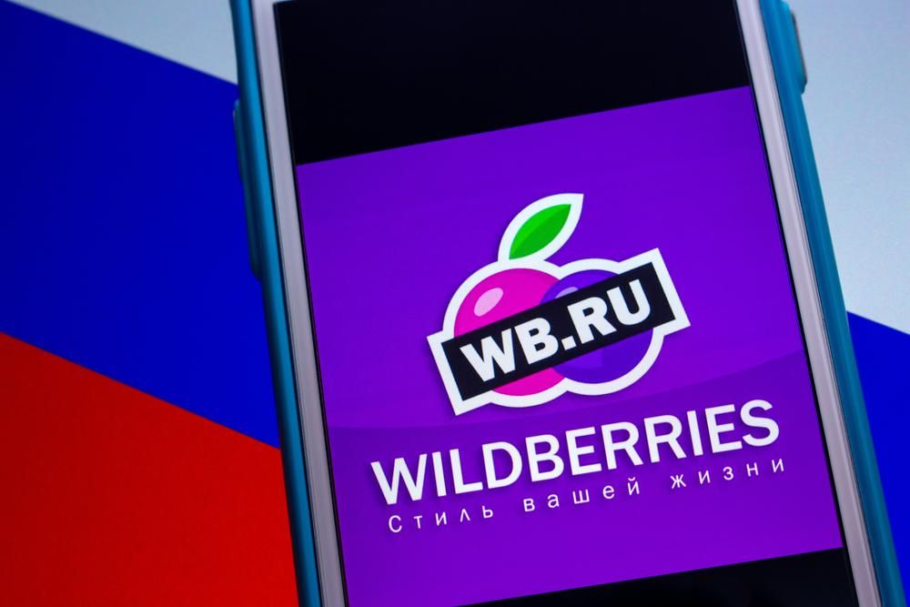 A Wilberries e-kereskedelmi cég applikációja egy telefonon az orosz zászló előtt