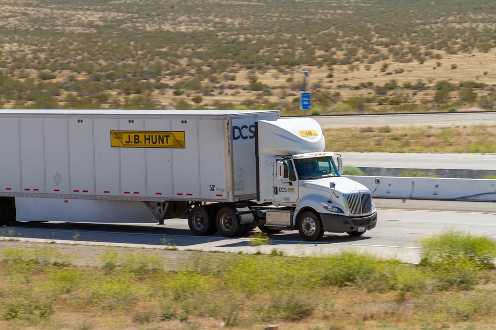 A J.B. Hunt teherfuvarozó vállalat egyik kamionja benne a kamionsofőrrel aki az autópályán, nappal vezeti a kamiont