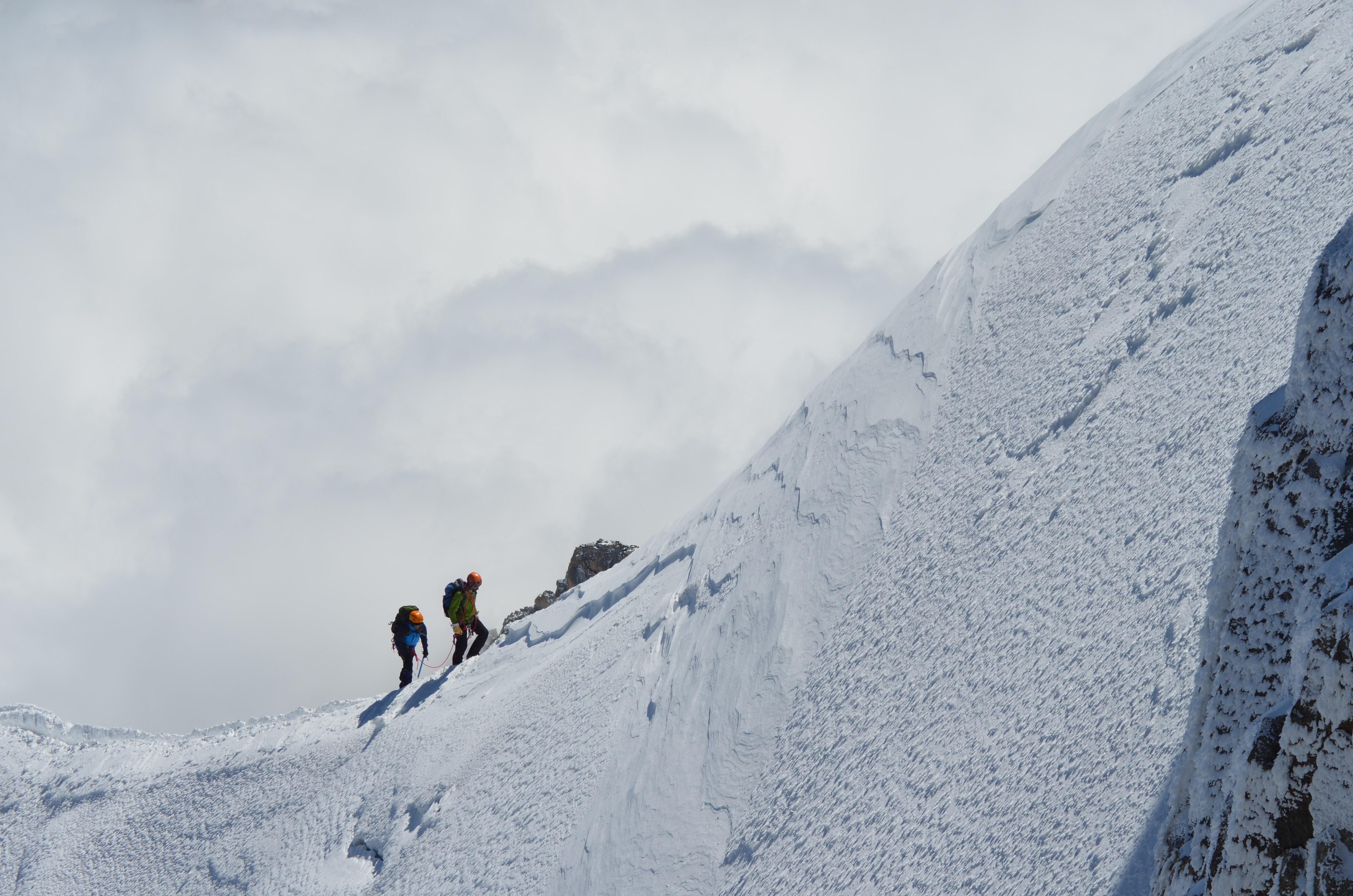Két hegymászó egy meredek hegyoldal aljából felfelé indul