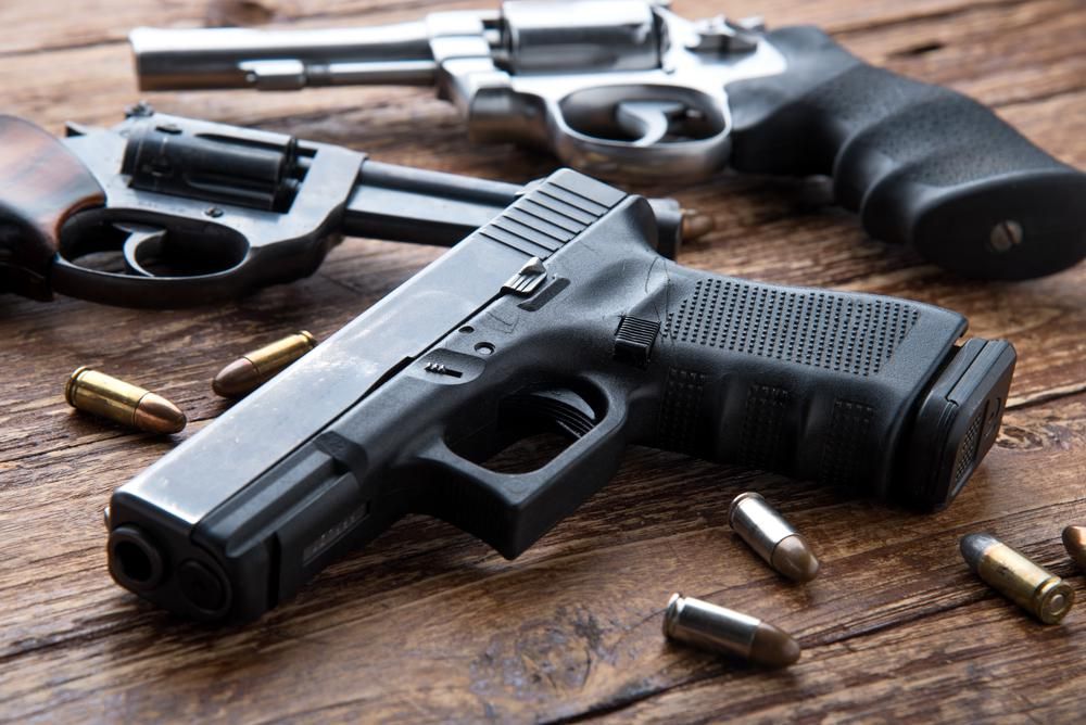9 milliméteres fegyver revolverekkel egy fa asztalon, amelyen lövedékek találhatók