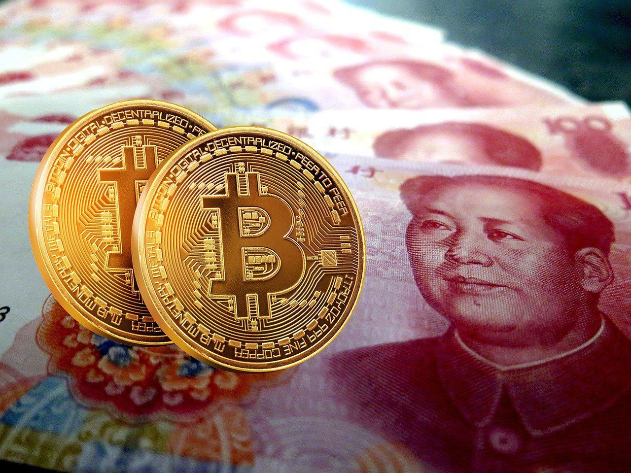 Két bitcoin látható több, sorba rendezett kínai jüan papírpénz előtt, Kína a kriptovaluták betiltása után NFT-blokkláncot épít