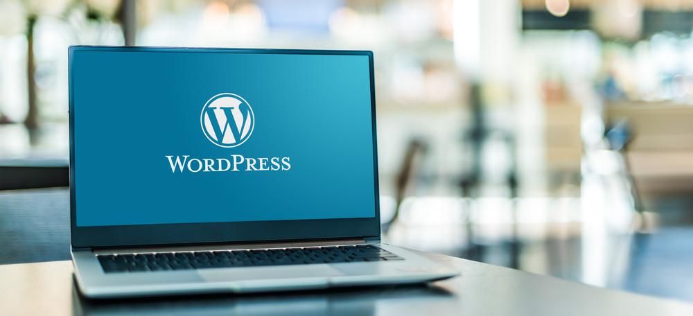 A WordPress logója egy laptopon, ami egy szürke asztalon van, a háttér homályos