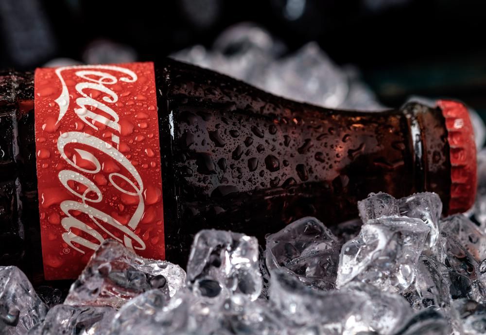 Egy üveg Coca-Cola elfektetve jégkockákon