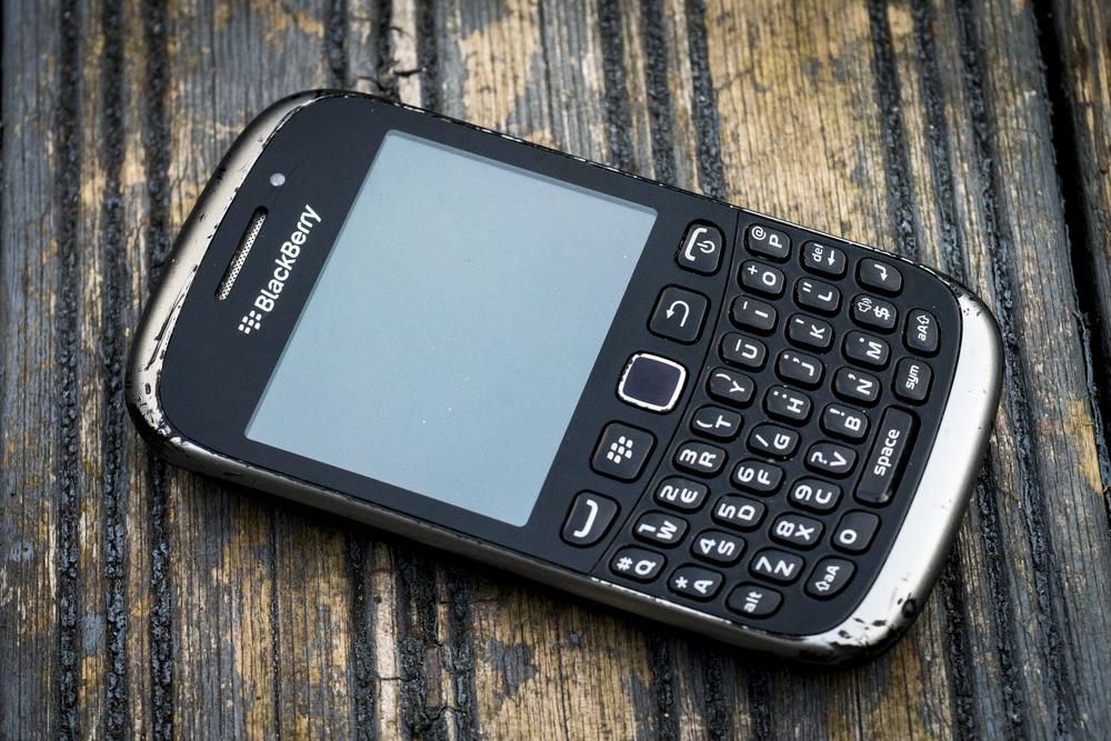 Kopottas, fekete színű BlackBerry egy szintén kopottas fa felületen