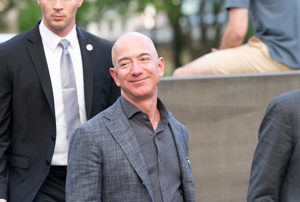 Jeff Bezos mosolyogva nézi új szuperjachtját szürke öltönyben