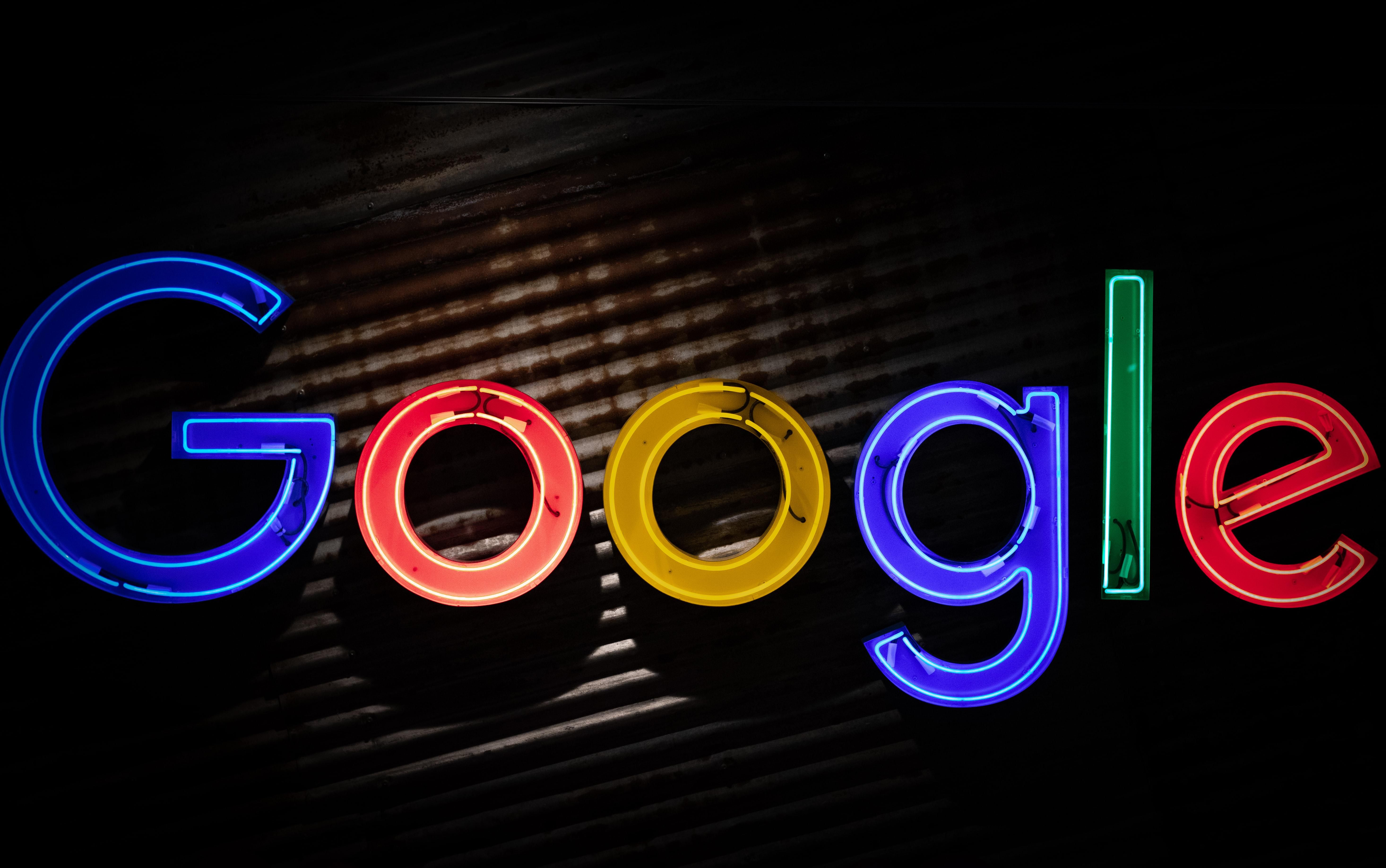 A Google logója kék, piros, sárga és zöld betűkkel, sötét felületen, középen megvilágítva