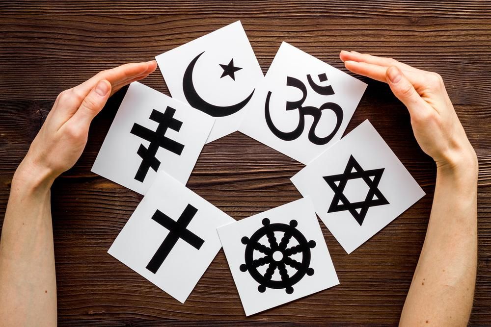 A kereszténység, a buddhizmus, a zsidó, a hinduizmus, az iszlám és az ortodox vallások szimbólumai két kéz között egy fa felületen