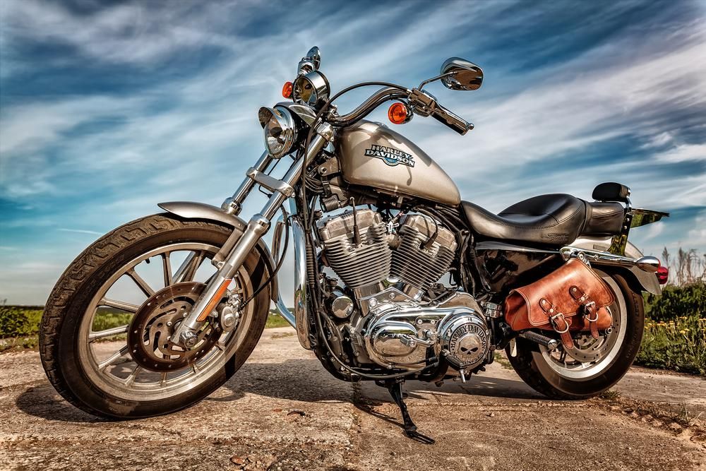 Szürke színű Harley-Davidson kitámasztva egy út közepén, napos időben