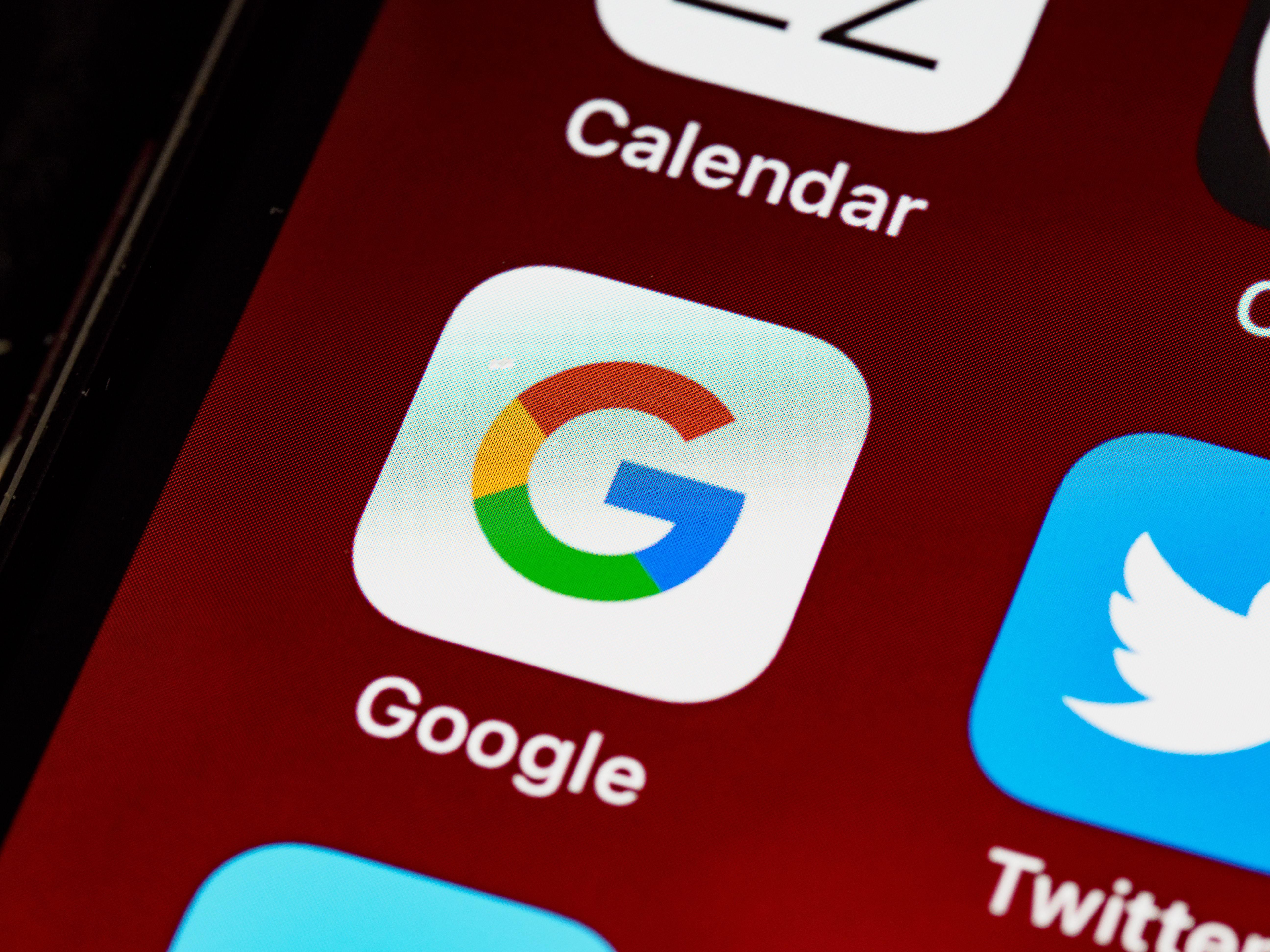 A Google logója egy okostelefon képernyőjén, mellette a Twitter és a Naptár logója látható