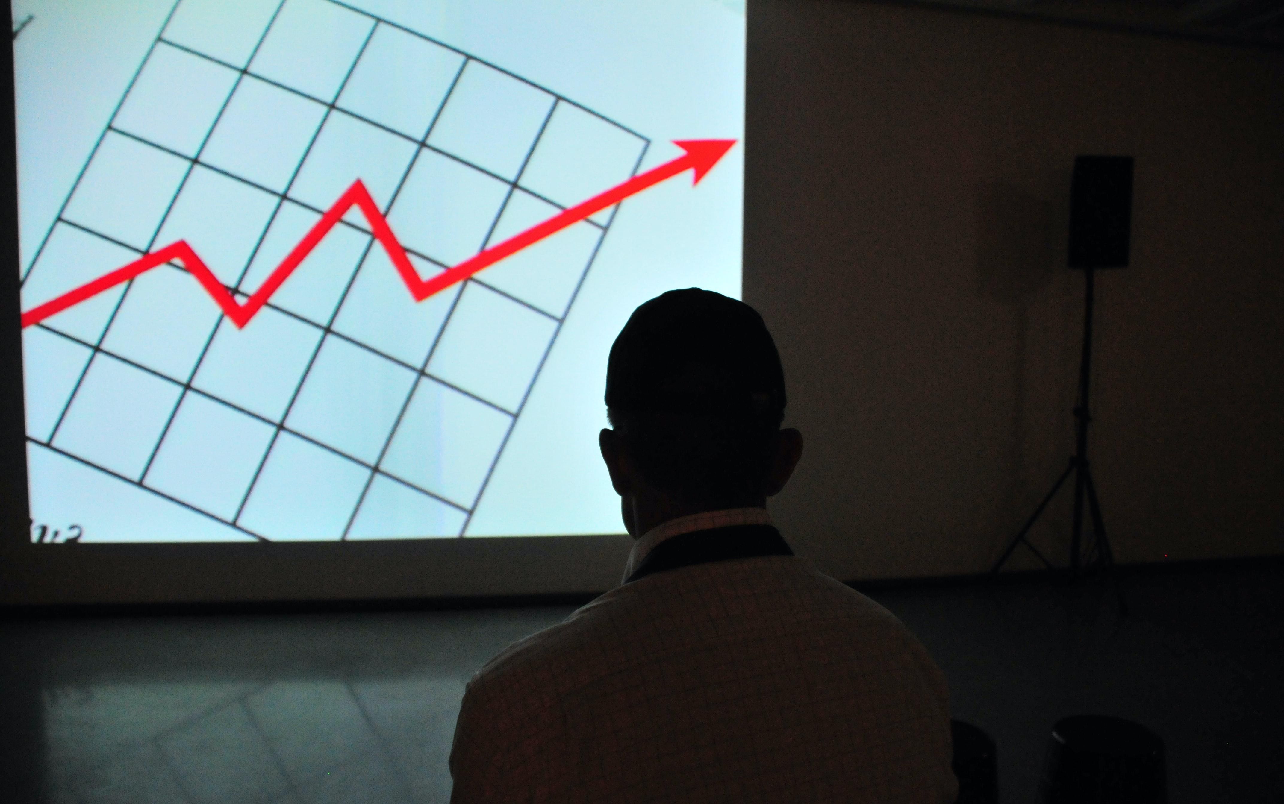Inges, nyakkendős ember egy sötét szobában nézi, ahogy a Securonix értékét jelző grafikon nyila kilő, miután 1 milliárd dolláros befektetéshez jutott