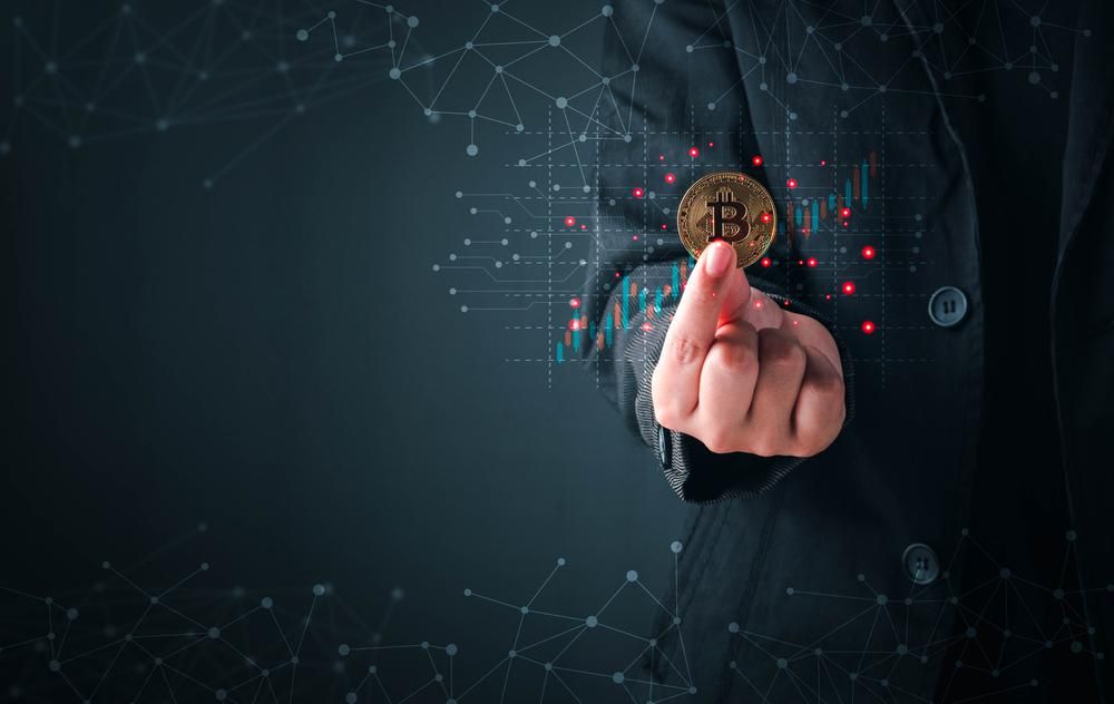 Egy öltönyös férfi a kezében tart egy bitcoin kriptovalutát, a kripto- és blokklánc cégek elhappolják a munkaerőt a nagy techcégek elől