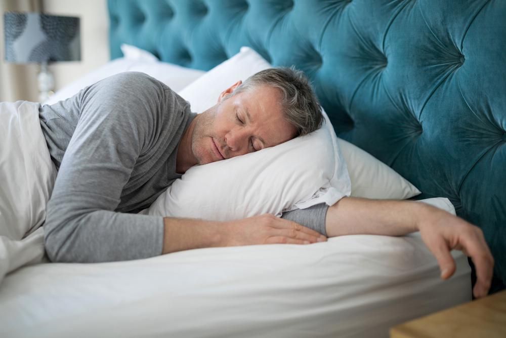 Egy szürke pizsamás férfi mélyen alszik, miután megfogadta tippeinket az álmatlansága ellen