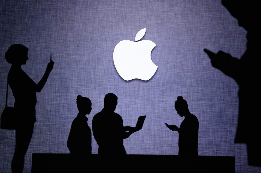 Emberek nyomkodják az iPhone-jaikat, Macbbokjaikat az Apple logója alatt, miután bemutatták az j olcsó iPhone-okat