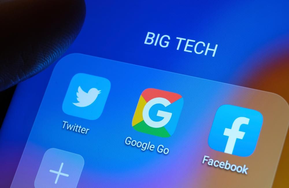 Nagy techcégek, a Twitter a Google és a Facebook logója egy brit polgár telefonjának képernyőjén