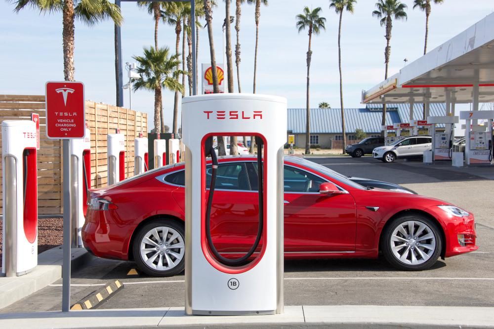 Egy piros színű Tesla töltődig a Tesla Supercharger töltőállomásán, a vállalat anyagilag támogatja ukrán dolgozóit