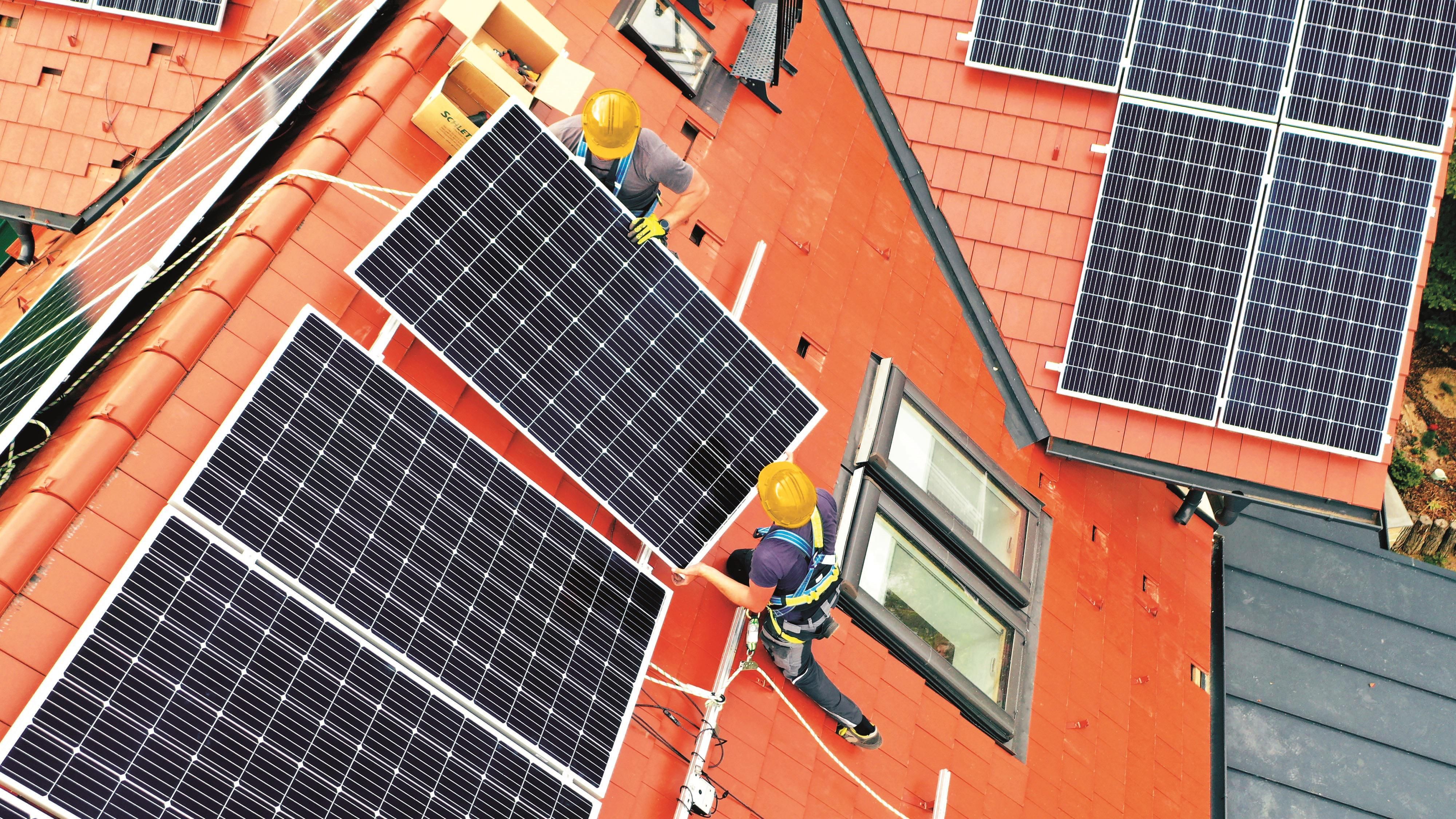 Két munkás napelemet szerel egy tetőre