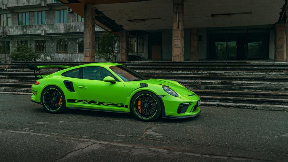 Neonzöld Porsche 911 egy épület előtt, hamarosan érkezik a plug-in verziója
