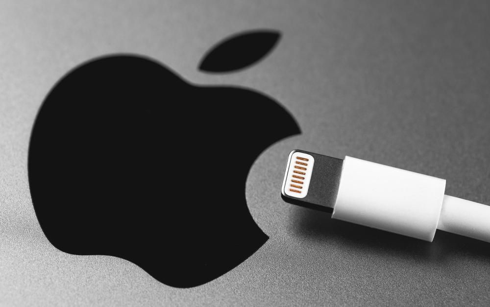 Az Apple logója egy iPhone hátulján, egy töltő van a logó közelében