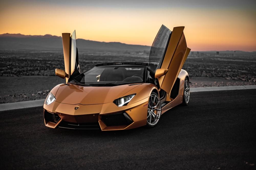 Sárga Lamborghini nyitott ajtókkal egy úton, naplementében, egyhamar nem lesz a szuperautóból teljesen elektromos változat