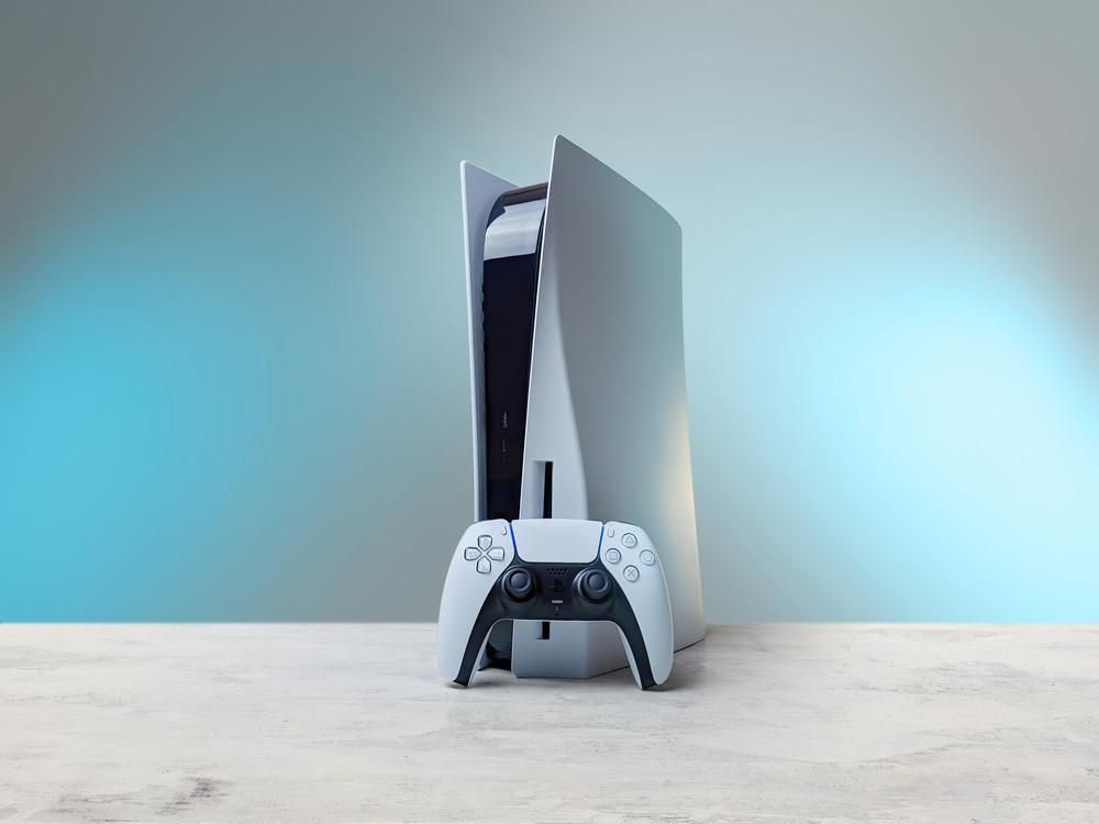 A Sony PlayStation 5 konzolja a hozzá tartozó joystickkal egy világos környezetben