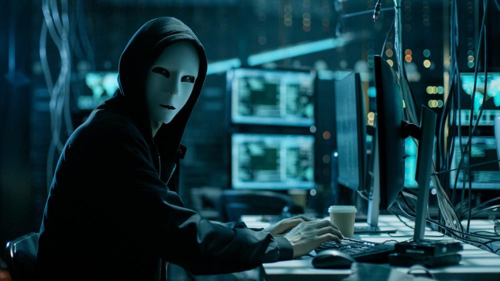 Maszkos, kapucnis hacker néz a kamerába, miután 625 millió dollárnyi kriptovalutát ellopott.