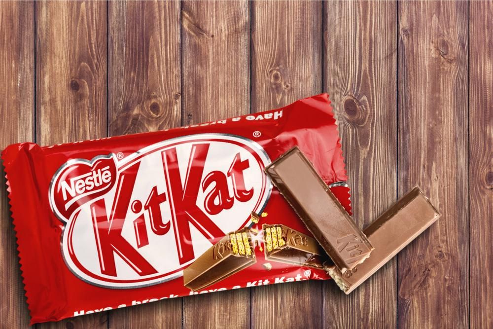 Piros KitKat csokoládé félig kibontva egy fa asztalon