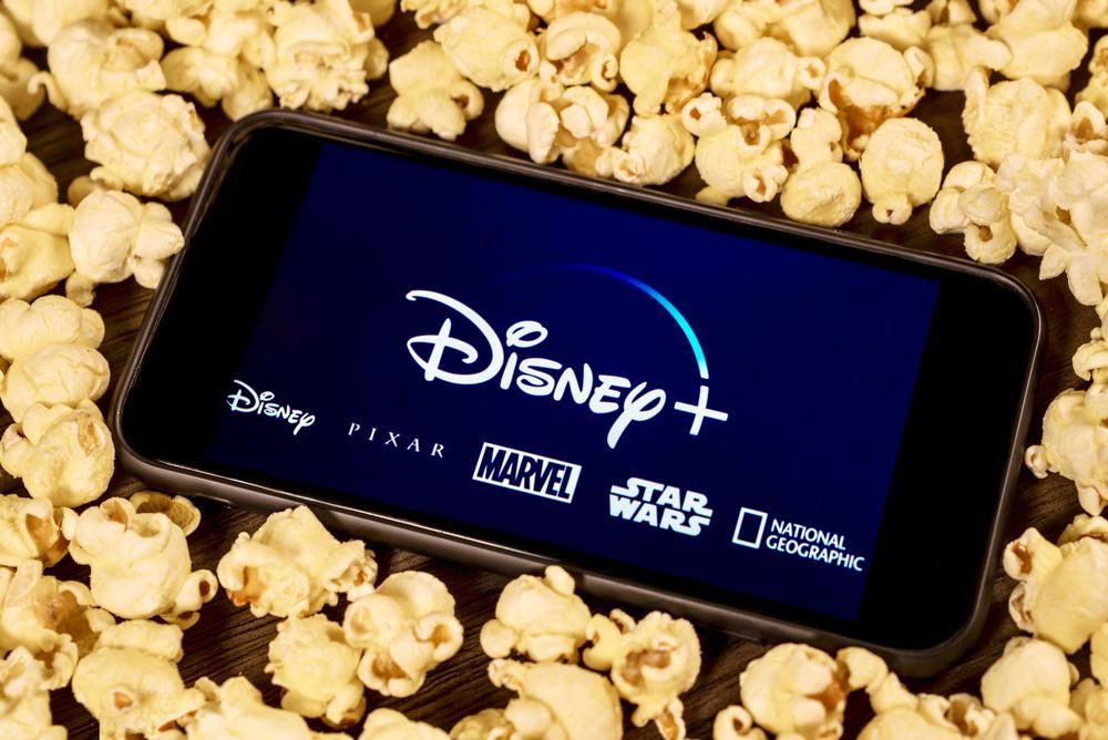 Okostelefonon Disney+ alkalmazás, körülötte popcorn
